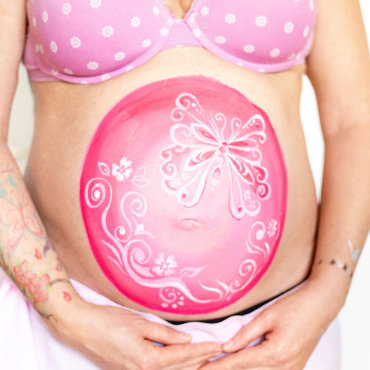 Bemalung auf Schwangerschaftsbauch mit Schmetterling auf rosa Hintergrund