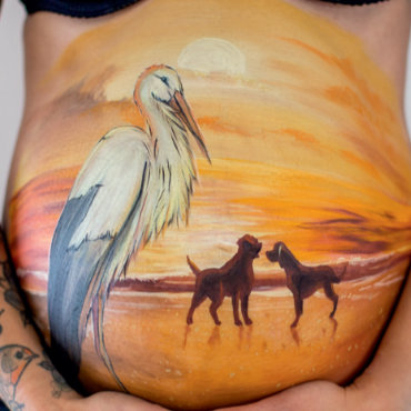 Bemalung auf Schwangerschaftsbauch mit Storch und Hunden