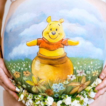 Bemalung auf Schwangerschaftsbauch mit Winnie Poo im Honigtopf